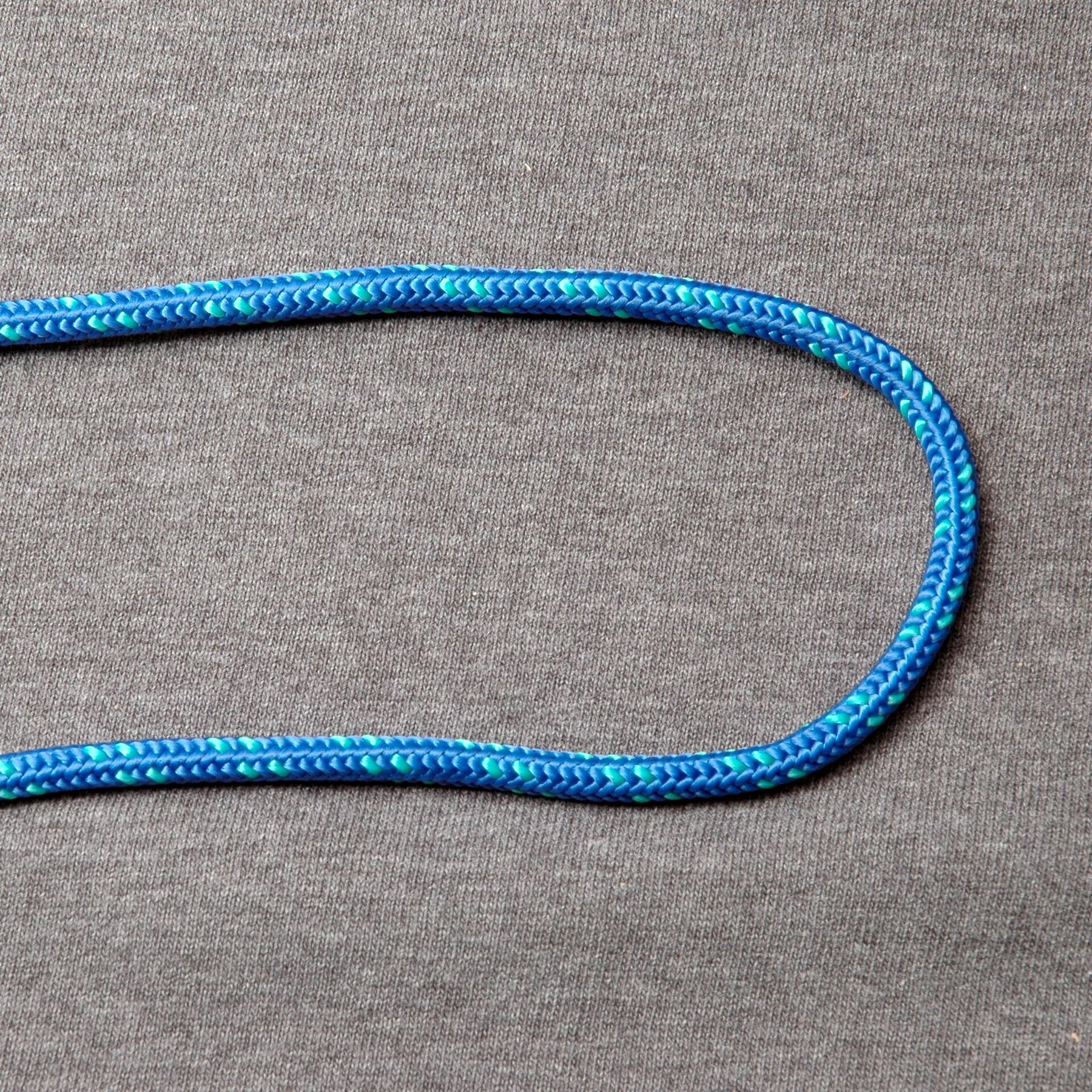 A blue braided rope lying on grey fabric, bent into a long U-shaped curve with both ends leaving the picture on the left.