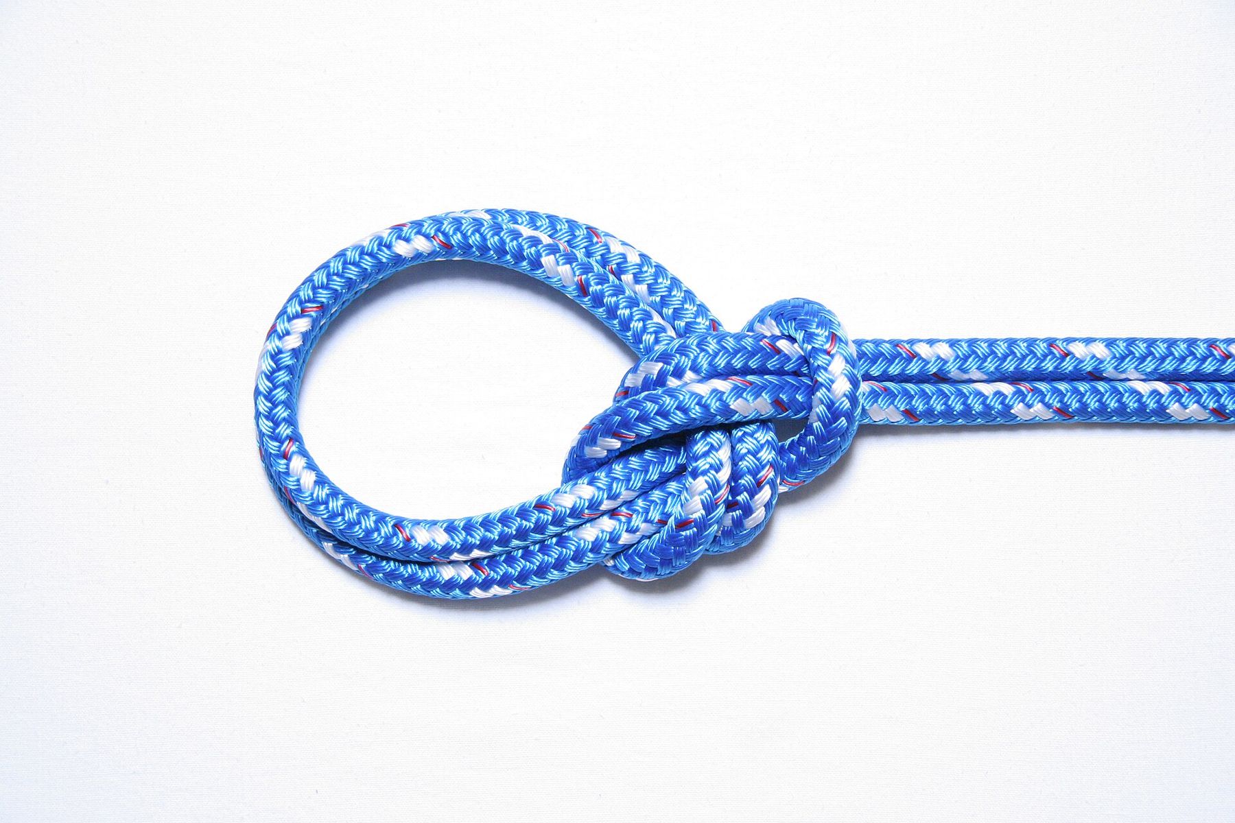 A finished knot in blue braided rope on a white background: two loops lie together on the left, gathered by a knot where the doubled rope continues to the right.